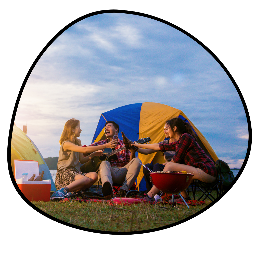 Three people enjoying a campfire in front of a blue and yellow tent with a clear sky.

